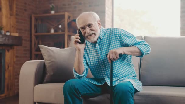 Allegro socievole pensionato uomo seduto divano tenere canna parlare telefono — Video Stock