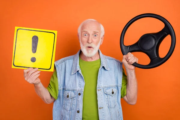 Φωτογραφία του χαριτωμένο εντυπωσιασμένος συνταξιούχος φορούν vintage τζιν γιλέκο κρατώντας τιμόνι σταματήσει χειρονομία πλακάτ απομονωμένο πορτοκαλί χρώμα φόντο — Φωτογραφία Αρχείου