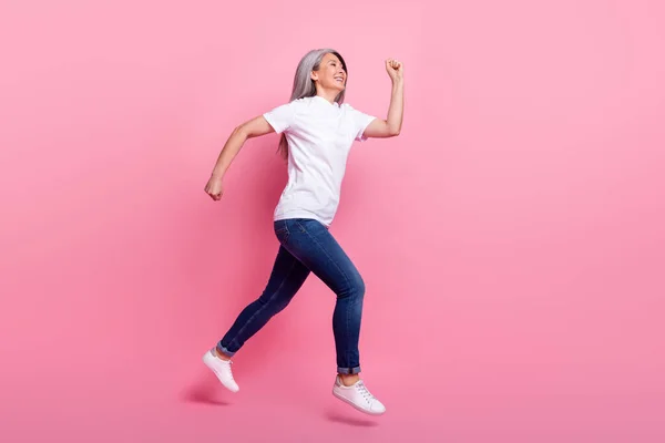 Vista completa del tamaño del cuerpo de la encantadora mujer alegre de pelo gris saltando corriendo aislada sobre el fondo de color pastel rosa —  Fotos de Stock