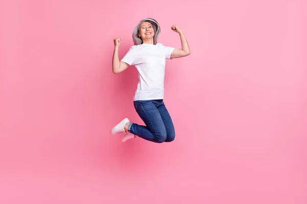 フル丈ボディサイズ写真の年上の女性ジャンプアップジェスチャーのような勝者喜び絶縁パステルピンク色の背景 — ストック写真