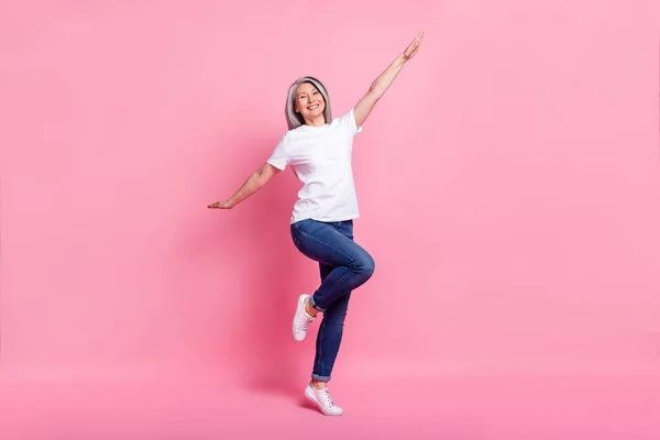 写真の光沢のあるファンキーな年齢の女性の服を着て白い服の笑顔ダンスジャンプ孤立したピンク色の背景 — ストック写真