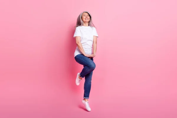 フル丈ボディサイズビューのかなり陽気な白髪の女性ジャンプ楽しいを持っていますピンクパステルカラーの背景に孤立 — ストック写真