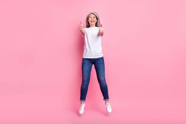 Full length body size photo of woman jumping up showing thumb-up sign isolated pastel pink color background — Stock Photo, Image