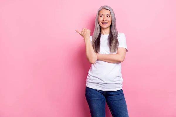 Photo of charming sweet mature lady wear white clothes pointing thumb up empty space smiling isolated pink color background — 图库照片