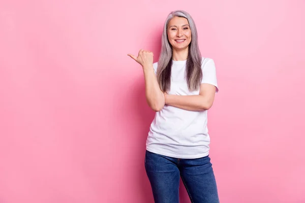 Foto portret van oudere zakenvrouw glimlachend tonen duim lege ruimte geïsoleerde pastel roze kleur achtergrond — Stockfoto