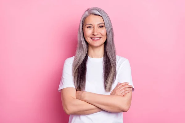 Retrato fotográfico de una mujer de negocios mayor sonriendo con las manos cruzadas aisladas sobre fondo de color rosa pastel —  Fotos de Stock
