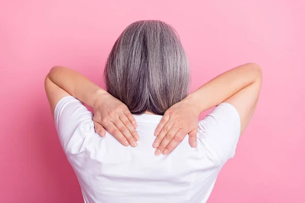 Задний вид фото портрет пожилой женщины трогательные плечи получили боли в спине изолированы на пастельно-розовом фоне — стоковое фото