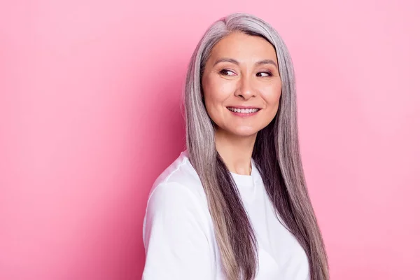 Foto portret van senior vrouw glimlachend dragen casual kleding op zoek lege ruimte geïsoleerd op pastel roze kleur achtergrond — Stockfoto