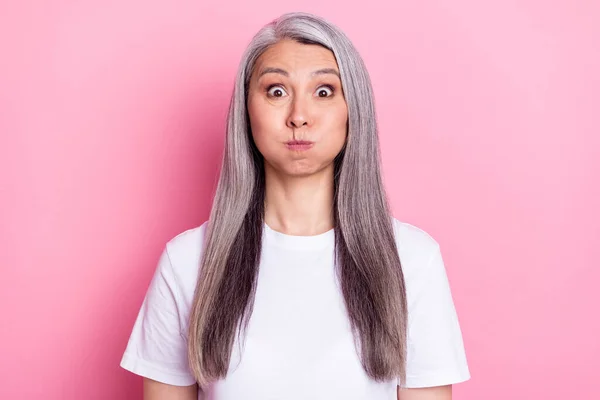 Portrait of nice attractive funny grey-haired woman holding air in cheeks fooling isolated over pink pastel color background — 图库照片