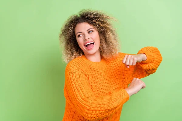 Фото враженої блондинки танцює виглядає промо-носіння помаранчевого пуловеру ізольовано на зеленому кольорі — стокове фото