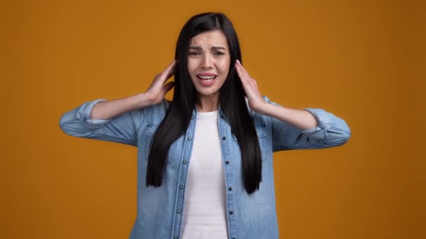 Moe dame verbergen oren vragen niet spreken geïsoleerd op oranje mosterd kleur achtergrond — Stockvideo
