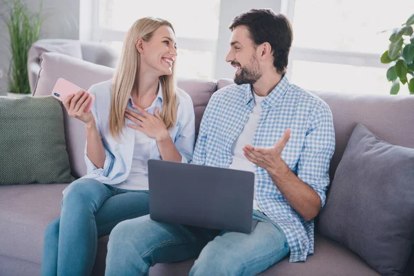 Photo of funny friendly couple sit couch share digital news wear casual outfit in comfortable home indoors — Stock Photo, Image