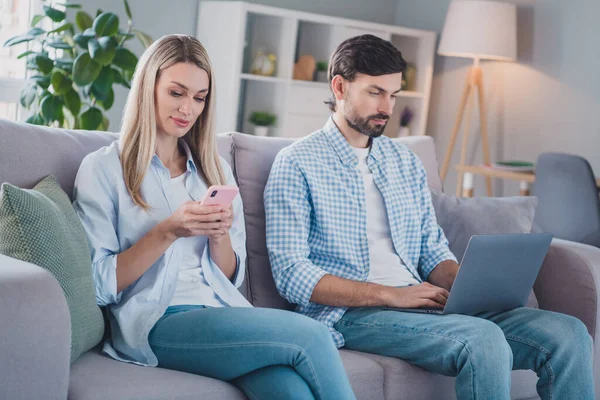 Foto de alegre pareja positiva enamorada sentarse sofá celebrar dispositivo digital desgaste traje casual en el hogar cómodo en interiores — Foto de Stock