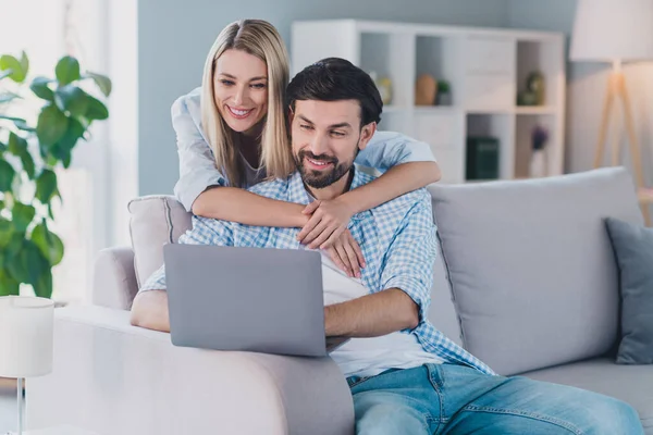 Foto de casal amante descontraído sincero sonhador sentar sofá olhar laptop vestir roupa casual em casa confortável dentro de casa — Fotografia de Stock