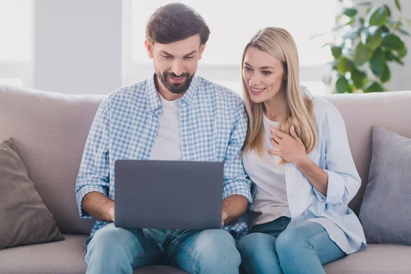 Fénykép a pozitív szerető pár két ember ül díván olvasni e-mail netbook viselni alkalmi ruhát kényelmes otthon beltéri — Stock Fotó
