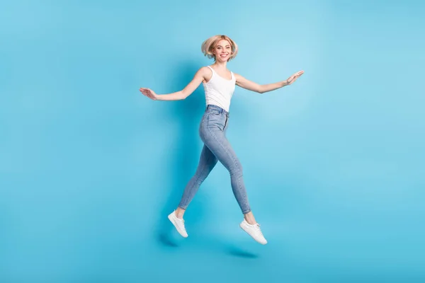 Teljes test profil oldalán fotó boldog fiatal vidám hölgy ugrás fel megy üres tér elszigetelt kék színű háttér — Stock Fotó