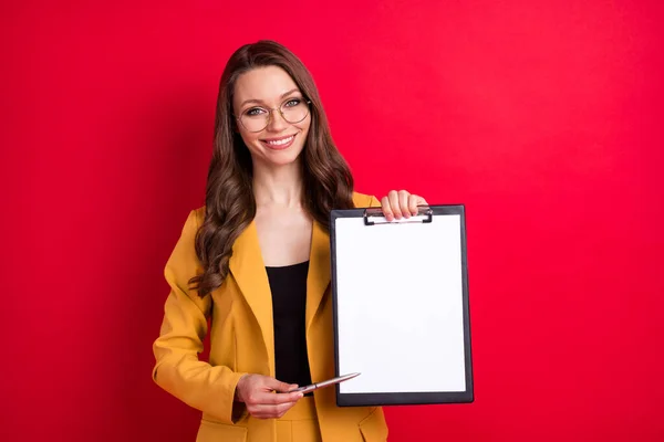 Retrato de atractiva dama alegre demostrando espacio de copia lugar para firmar contrato de la empresa aislado sobre fondo de color rojo brillante —  Fotos de Stock