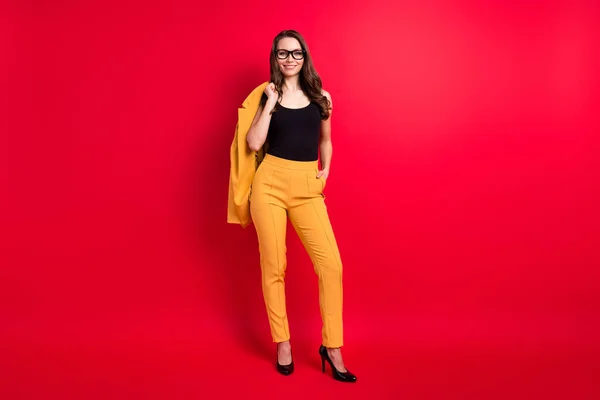 Plná délka tělo velikost pohled na atraktivní veselý elegantní dívka pózovat držení sako izolované přes jasně červené barvy pozadí — Stock fotografie