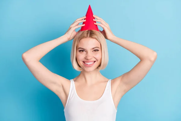Foto van tevreden meisje tand glimlach armen aanraken rood hoed kijken camera geïsoleerd op blauwe kleur achtergrond — Stockfoto