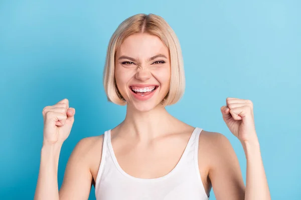 Foto de menina alegre surpreso punhos até o sorriso dos dentes grito sim isolado no fundo da cor azul — Fotografia de Stock