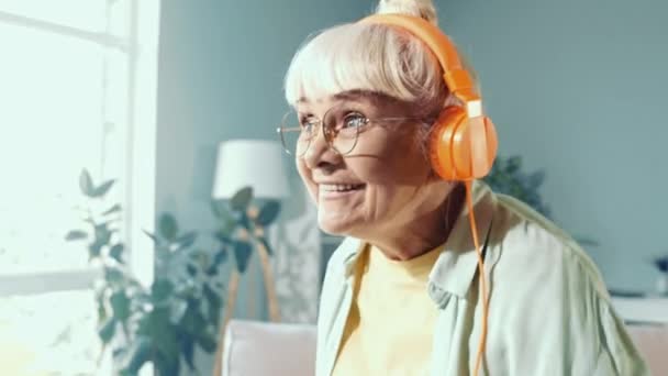 Alegre agradable relajado abuelita disfrutar de baile en casa escuchar auriculares audio — Vídeos de Stock