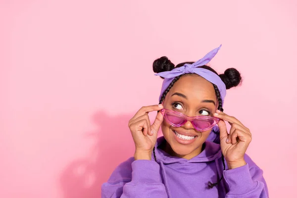 Photo of pretty attractive afro woman wear purple hoodie buns arms eyeglasses looking empty space smiling isolated pink color background