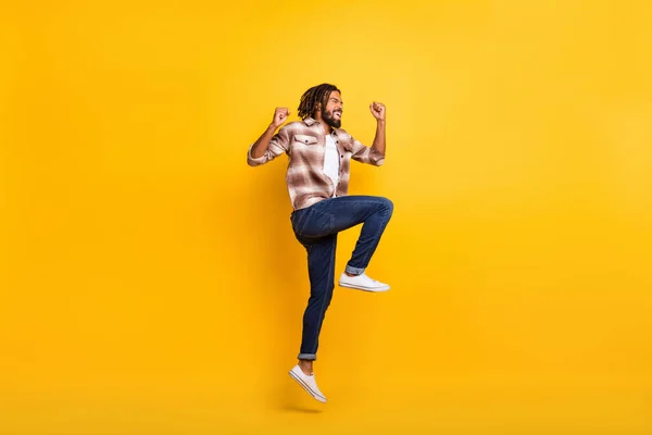 Foto de cuerpo de longitud completa del hombre saltando alto gesto como ganador de la lotería riendo aislado en el fondo de color amarillo vibrante —  Fotos de Stock