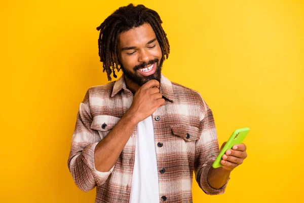 Foto retrato de homem barbudo usando smartphone tocando queixo navegando notícias na internet isolado no fundo de cor amarelo vívido — Fotografia de Stock