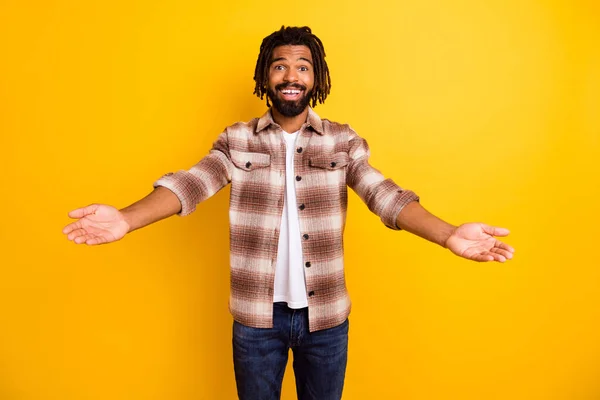 Foto porträtt av skäggig man inbjudande med öppnade händer ler glad i rutig skjorta isolerad på levande gul färg bakgrund — Stockfoto