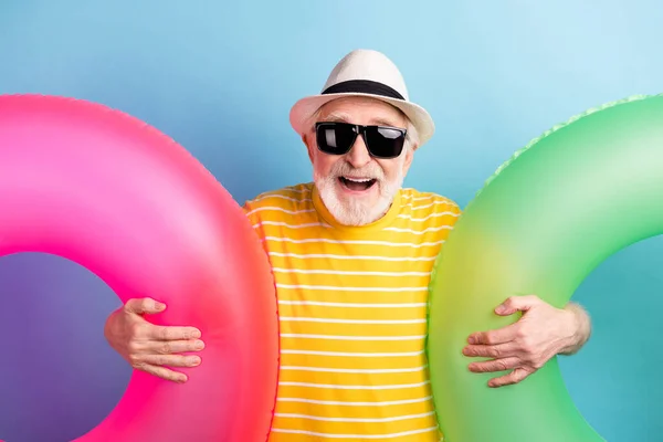Fénykép vidám pozitív boldog öregember viselni kalap kéz körök úszó jó hangulat utazás elszigetelt kék színű háttér — Stock Fotó