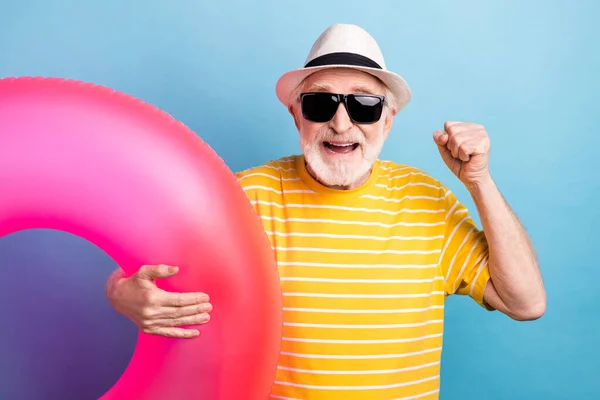 Porträtt av äldre pensionerad glad man håller gummi ring har roligt resort isolerad över klarblå färg bakgrund — Stockfoto