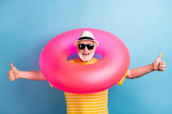 Foto von fröhlichen grauhaarigen alten Mann tragen gelb gestreiften T-Shirt Kreis Urlaub machen Daumen nach oben isoliert auf blauem Hintergrund — Stockfoto