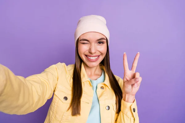 Foto ritratto di sorridente ragazza prendendo selfie in abiti casual mostrando gesto v-segno ammiccando isolato su sfondo di colore viola pastello — Foto Stock