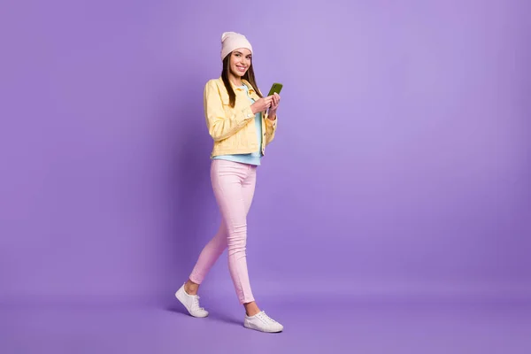 Teljes hossz testméret fotó csinos lány gazdaság mobiltelefon gépelés üzenet elszigetelt pasztell lila szín háttér — Stock Fotó