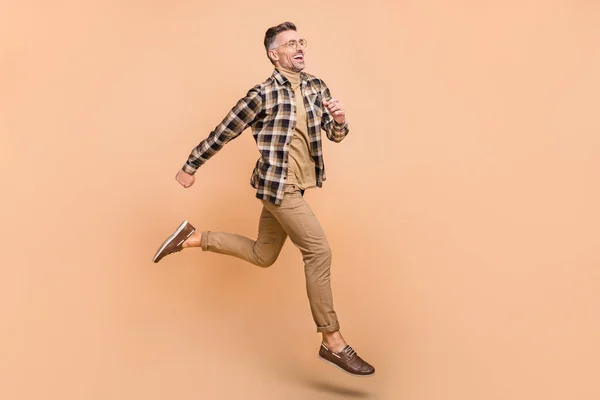 Volledig lichaam profiel zijkant foto van vrolijke man run look lege ruimte beweging rush geïsoleerd over beige kleur achtergrond — Stockfoto