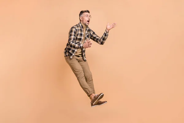 Полный профиль тела боковой фотографии изумленный зрелый мужчина прыгун реакции выглядят пустое пространство изолированы на бежевом фоне цвета — стоковое фото