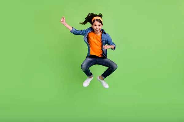 Foto de encantadora chica estudiante bonita usar camisa de mezclilla sonriendo saltando caballo de alta equitación aislado color verde fondo —  Fotos de Stock