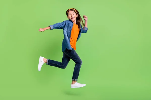 Foto de funky dulce niña preadolescente vestido jeans camisa corriendo rápido saltando alto sonriente aislado color verde fondo — Foto de Stock