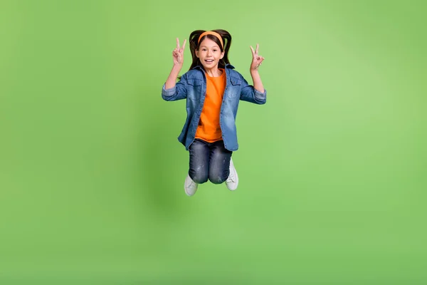写真の可愛いですファンキーなpreteen女の子服ジーンズシャツショーv-signジャンプ高い笑顔隔離された緑の背景 — ストック写真