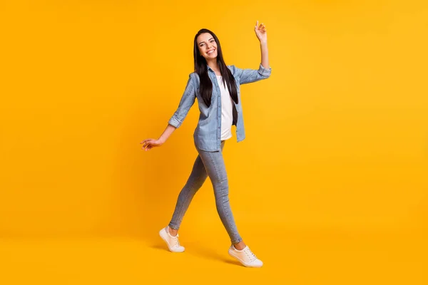 Foto de perfil em tamanho completo de boa senhora morena otimista ir usar tênis jeans camisa azul isolado no fundo de cor amarela — Fotografia de Stock