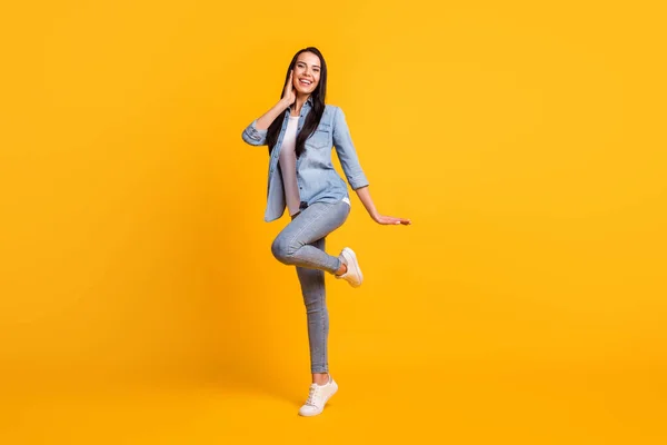 Foto de tamaño completo de adorable niña satisfecha bailando levantar la sonrisa dentada de la rodilla aislado en el fondo de color amarillo —  Fotos de Stock