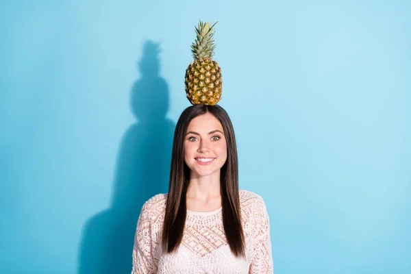 かなり若い魅力的な女性の写真は、青の色の背景に隔離された頭の上にバランスパイナップルを保持 — ストック写真