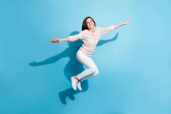 Full kropp foto av glada glad ung kvinna hoppa upp luft håll händerna plan vingar isolerade på blå färg bakgrund — Stockfoto