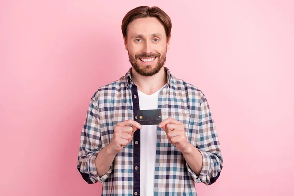 Foto do jovem feliz sorriso positivo segurar o lucro do cliente do pagamento do cartão bancário isolado sobre fundo cor-de-rosa — Fotografia de Stock