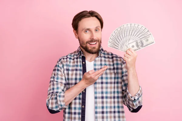 Foto van jonge man gelukkig positieve glimlach show hand geld geld dollars rijk geïsoleerd over roze kleur achtergrond — Stockfoto