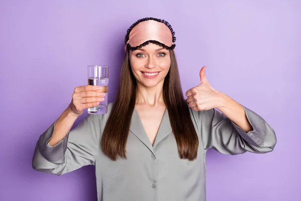 Портрет милой модной уверенной в себе веселой девушки носить пижамную питьевую воду показывая эскиз объявления изолированы на фиолетовый фиолетовый цвет фона — стоковое фото