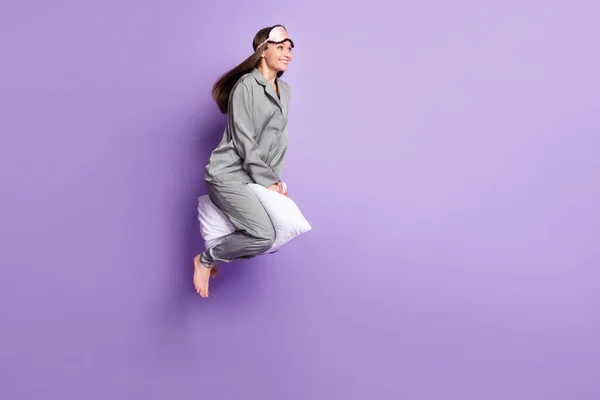 Foto de cuerpo entero tamaño de la mujer curiosa cabalgando en la almohada usando pijama gris buscando copyspace aislado pastel color púrpura fondo — Foto de Stock