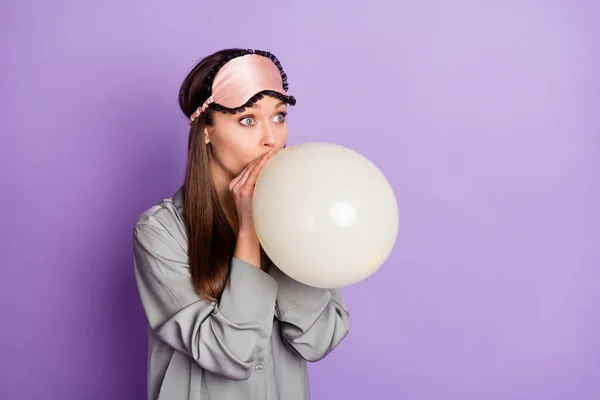 Foto-Porträt einer Frau im Pyjama Schlafmaske weht Luftballon suchen leeren Raum isoliert auf pastellvioletten Hintergrund — Stockfoto