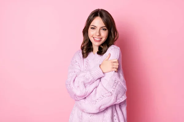 Фото очаровательной молодой леди в трикотажном пуловере, обнимающей себя изолированным пастельно-розовым цветом фона — стоковое фото