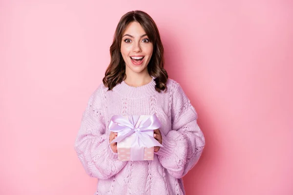 Портрет милой изумленной веселой девушки, держащей в руках подарочную коробку, изолированную на розовом пастельно-голубом фоне — стоковое фото